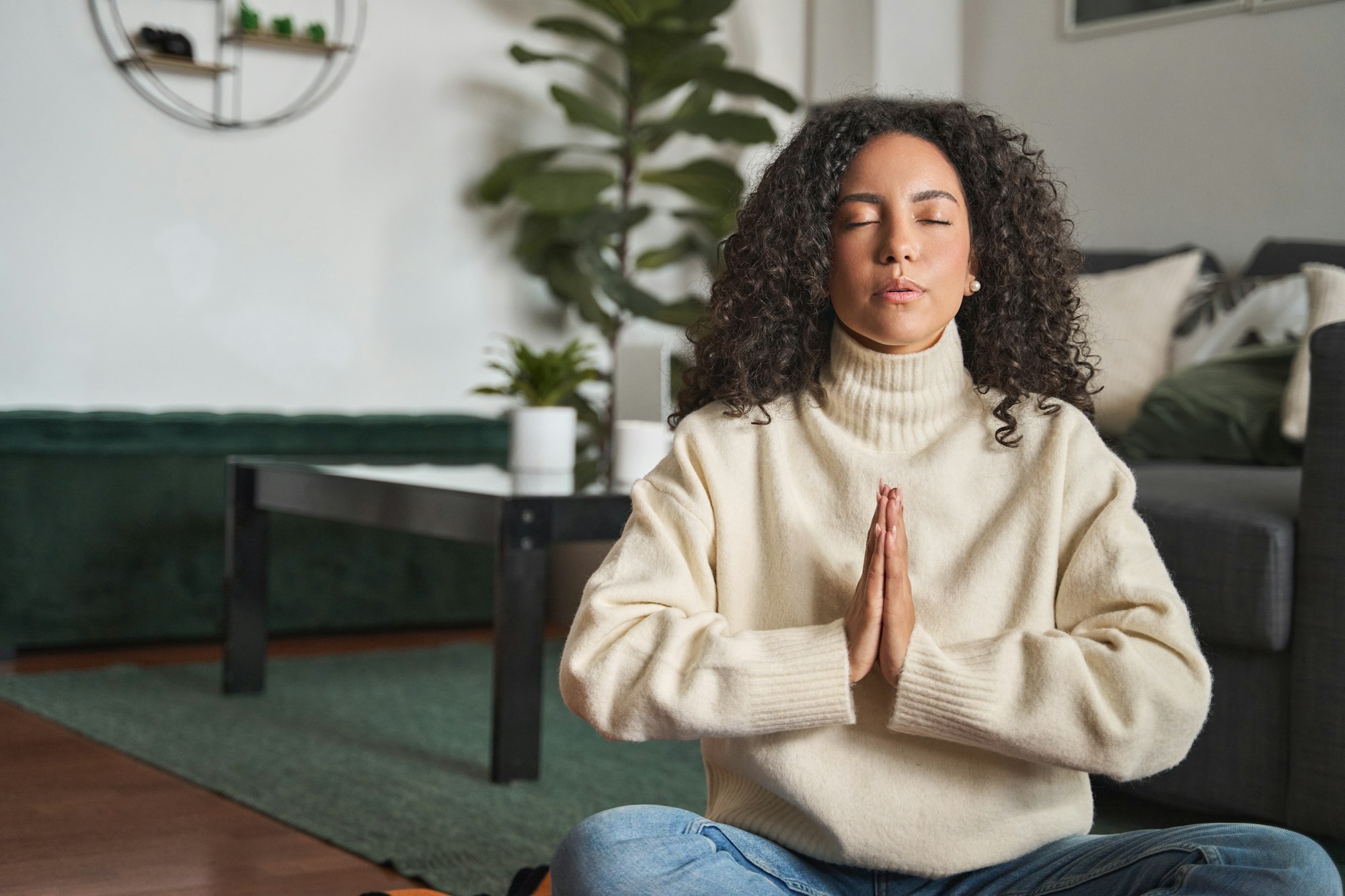 Young calm latin woman doing meditation breathing exercise at home.